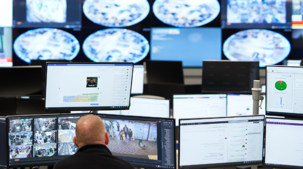 Man examining security footage on a bank of screens